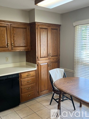 A kitchen with wooden cabinets and a black dishwasher.