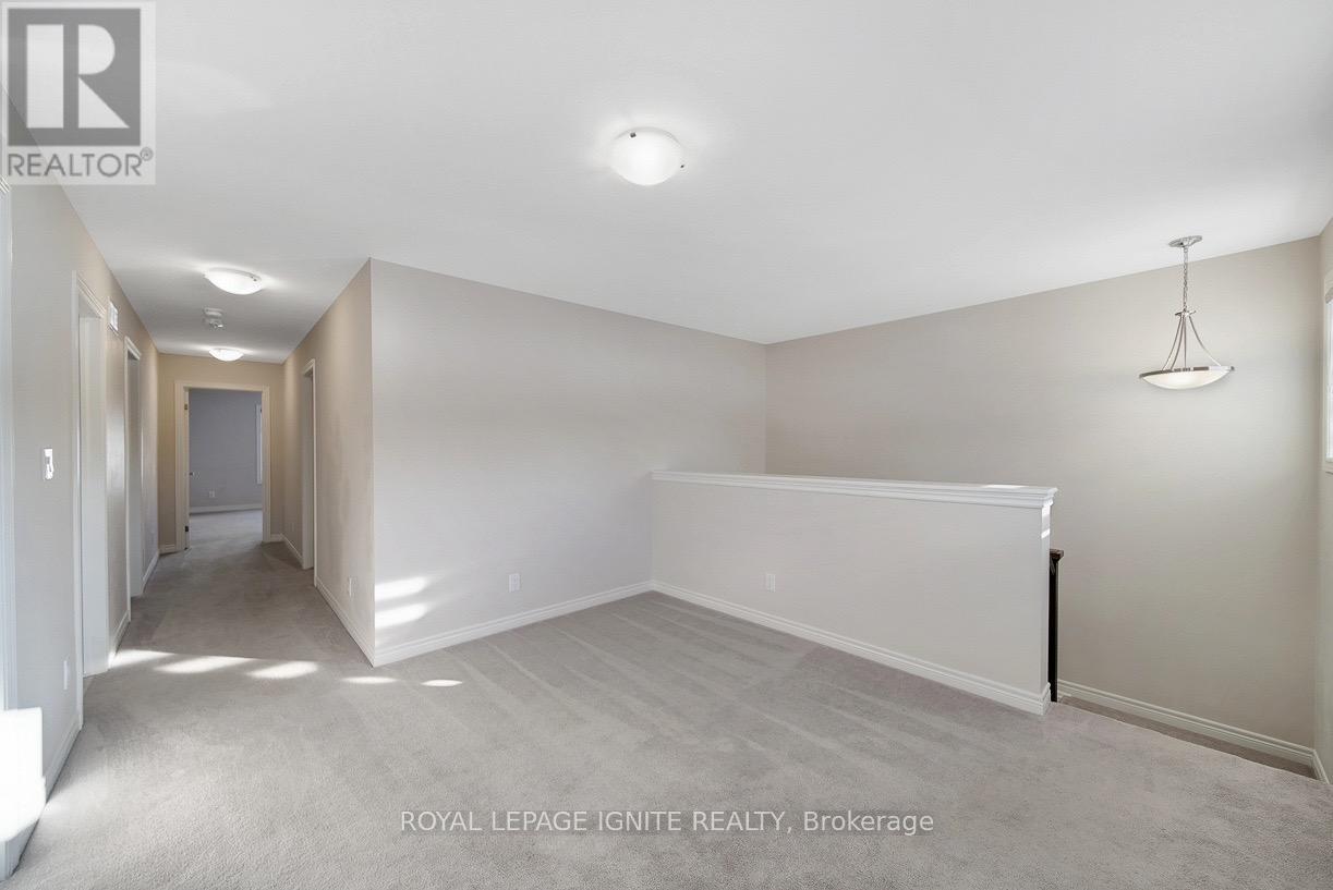 A spacious room with a carpeted floor and white walls, with a doorway leading to another room.