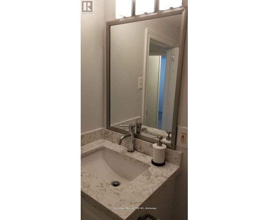 A bathroom with a marble sink and a large mirror.