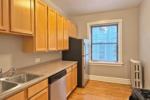 A kitchen with wooden cabinets and a black refrigerator.