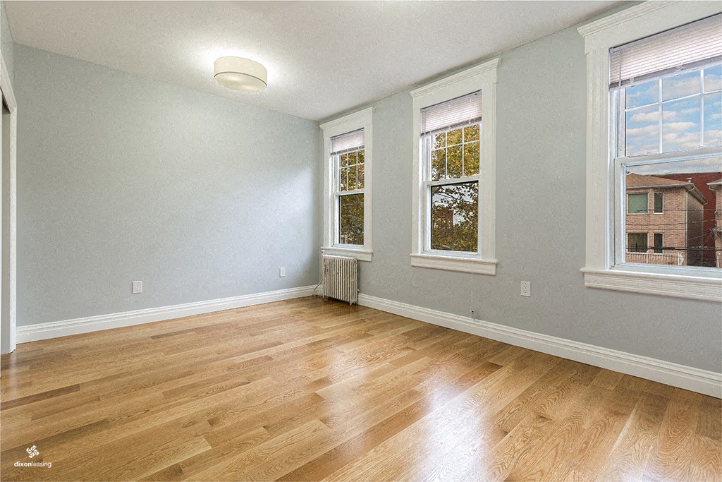 an empty living room with wood floors and three windows