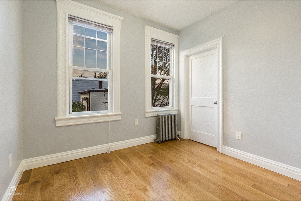 a bedroom with a door and three windows and a wood floor