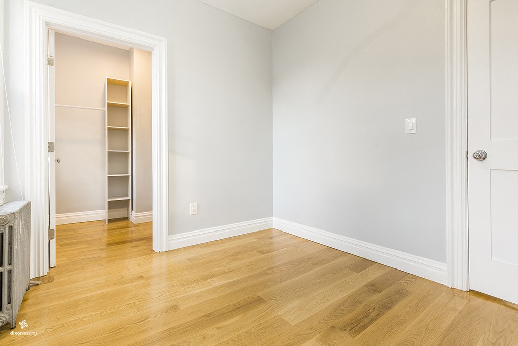 an empty room with white walls and wooden floors and a closet
