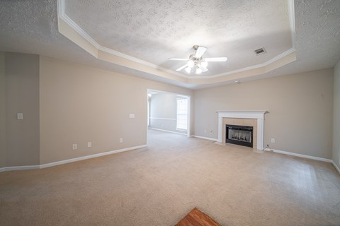 A living room with a fireplace and a ceiling fan.