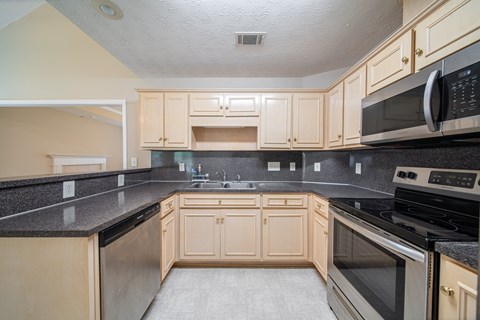 A kitchen with wooden cabinets and black countertops.