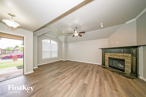 A spacious living room with a fireplace and wood flooring.
