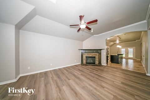 A spacious room with a fireplace and a ceiling fan.