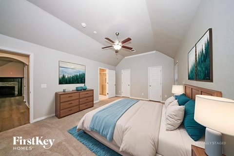 A bedroom with a bed, dresser, and ceiling fan.