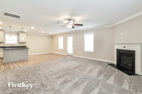 A spacious living room with a fireplace and a ceiling fan.