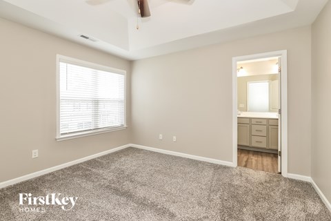 A spacious room with a carpeted floor and a ceiling fan.