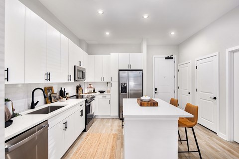 A modern kitchen with white cabinets and a wooden island.