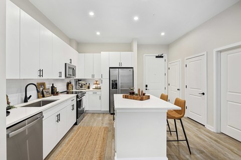 A modern kitchen with white cabinets and a wooden island.
