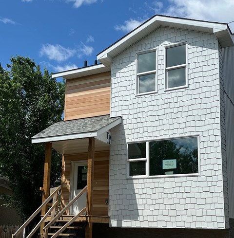 A white house with a brown wooden deck.