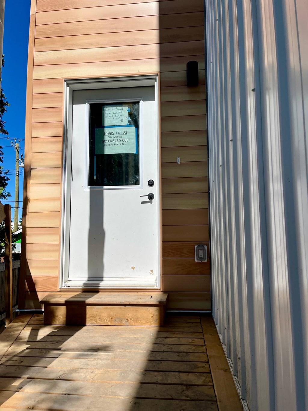 A white door with a glass window is on a tan building.