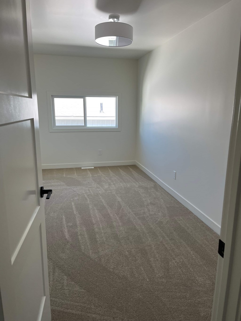 A room with a carpeted floor and a window.