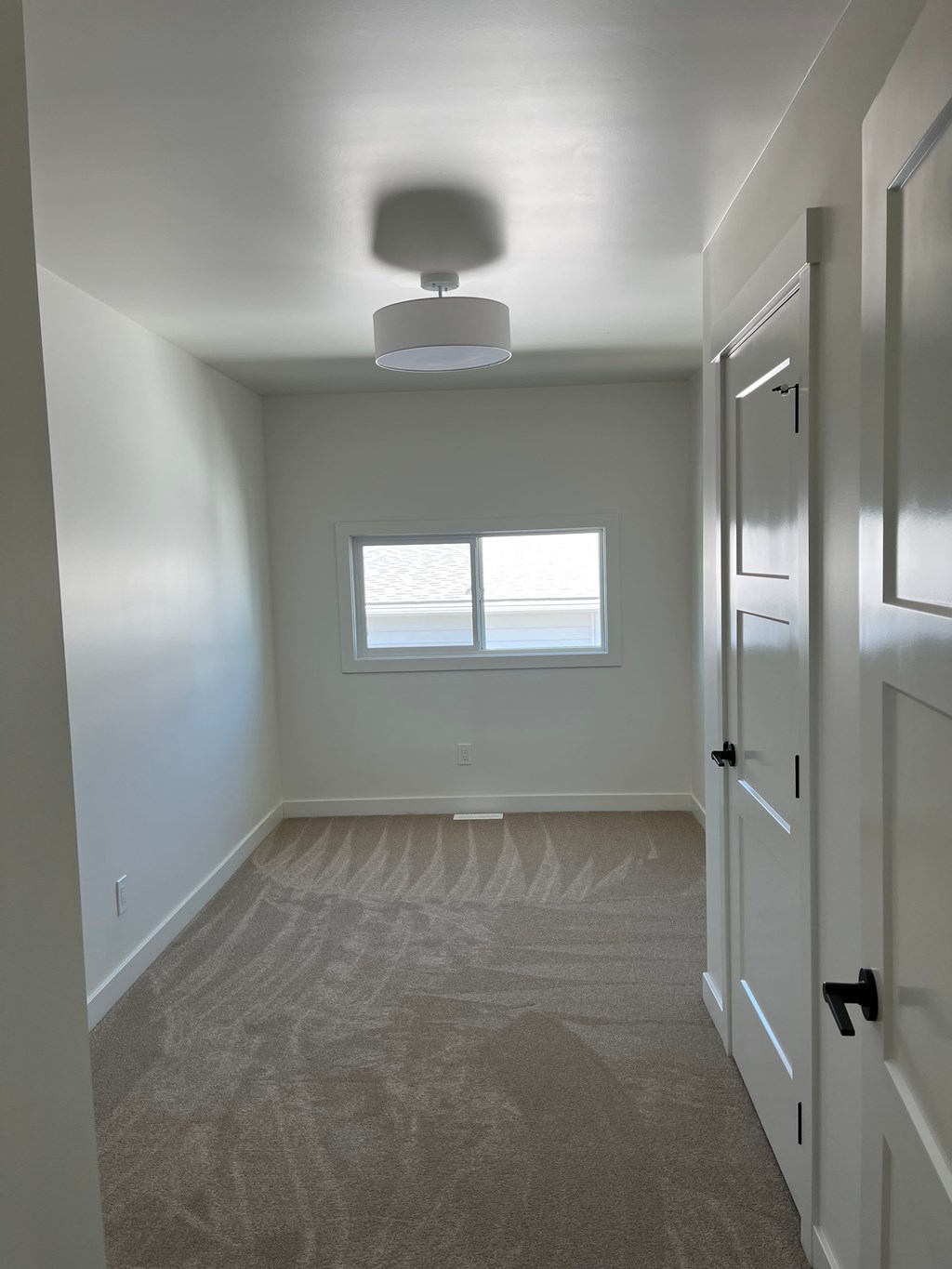A room with a carpeted floor and a window.