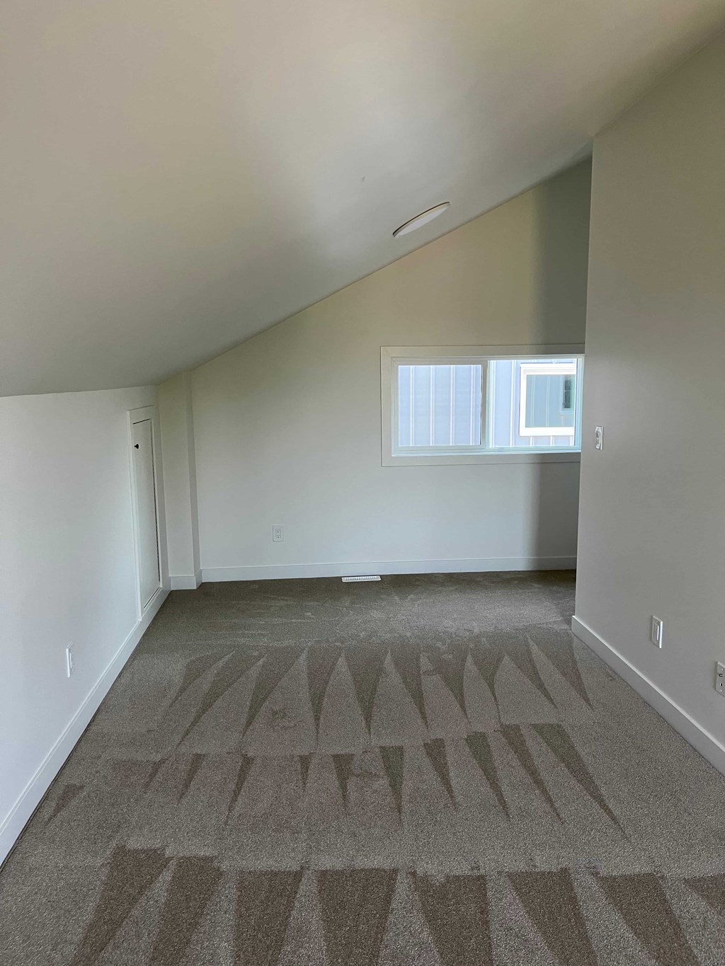 A room with a carpet and a window.