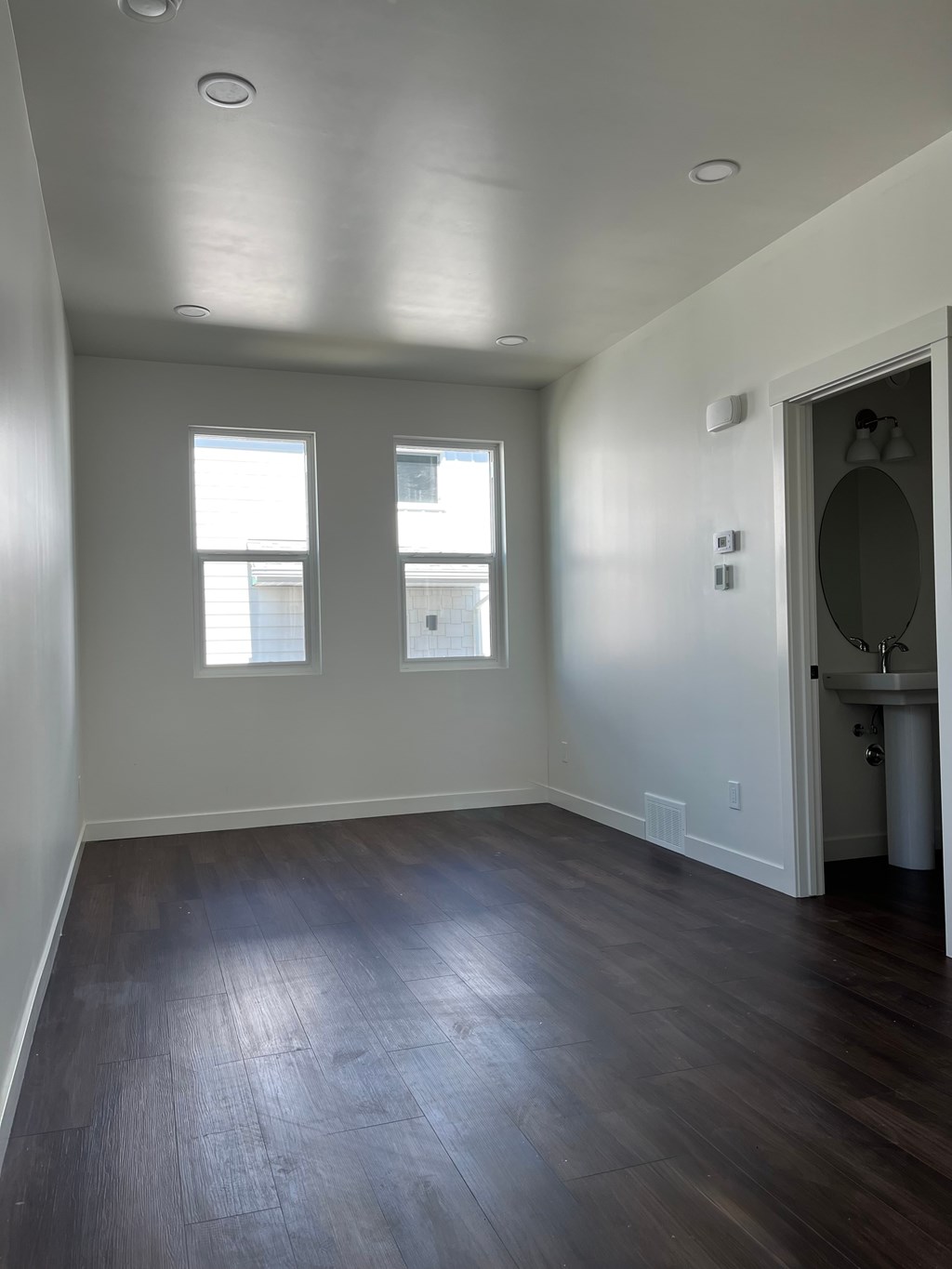 A room with wooden floors and two windows.