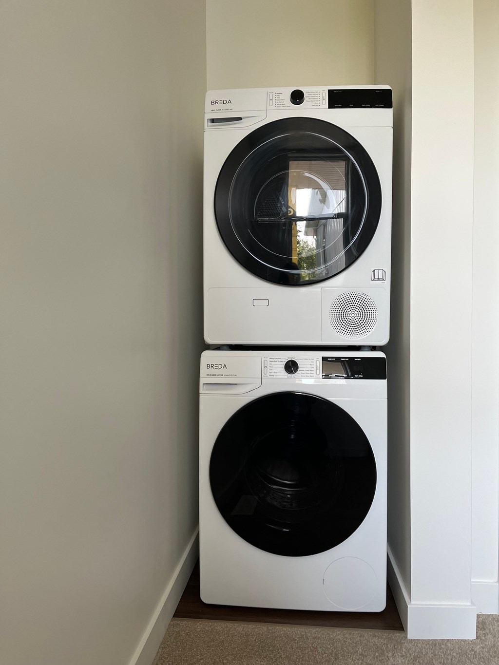 Two white front loading washing machines stacked on top of each other.