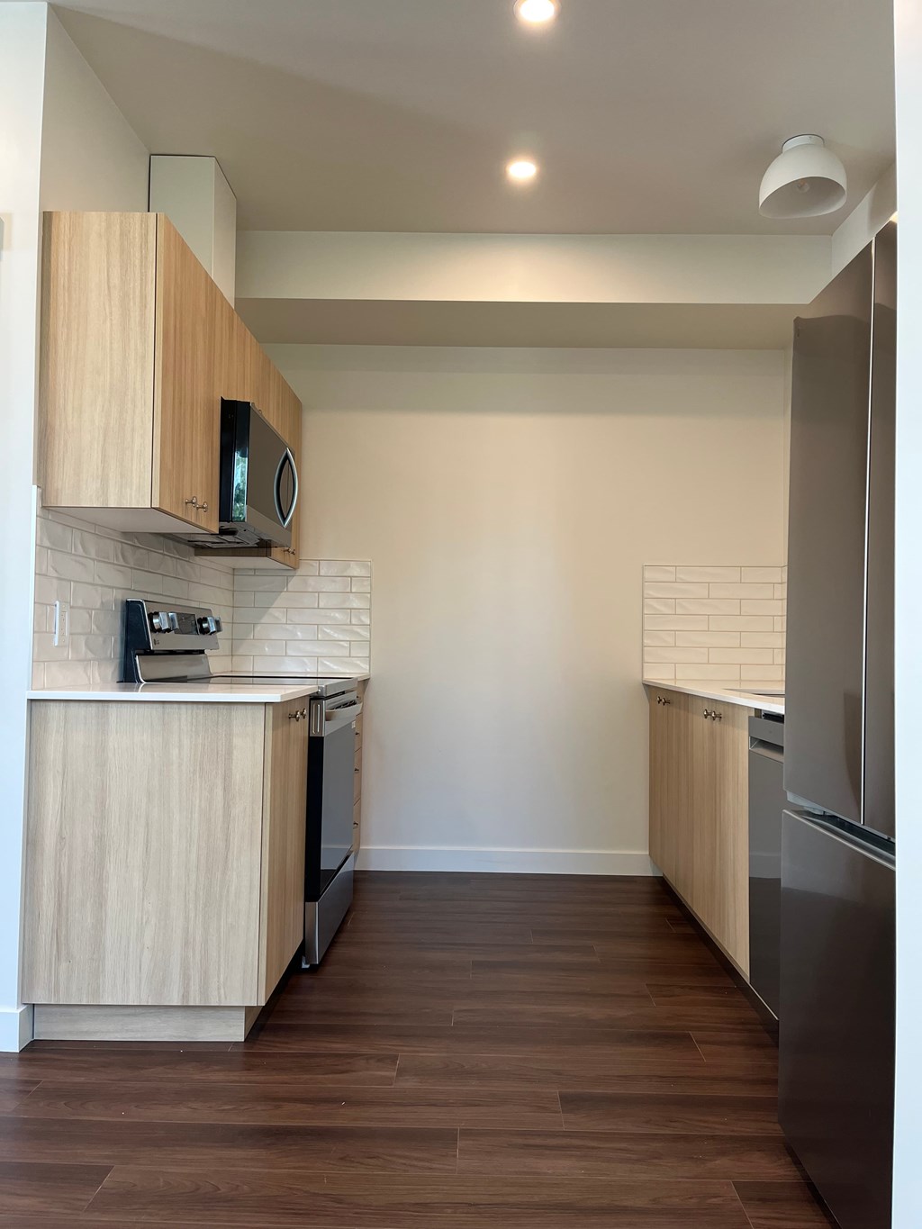 A kitchen with wooden cabinets and a stainless steel refrigerator.
