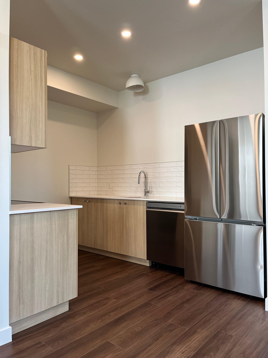 A modern kitchen with a stainless steel refrigerator and wooden cabinets.