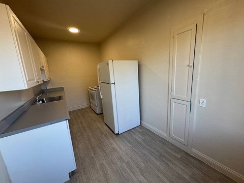 A kitchen with white cabinets and a white refrigerator.