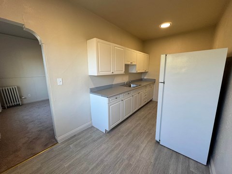 A kitchen with white cabinets and a white refrigerator.