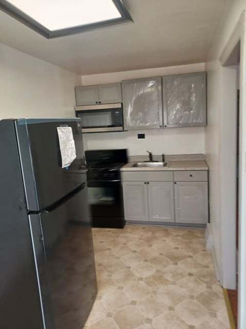 A kitchen with a black fridge and a black oven.