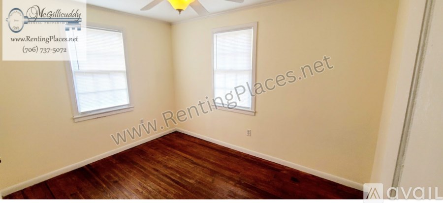 A room with wooden floors and two windows is available for rent.