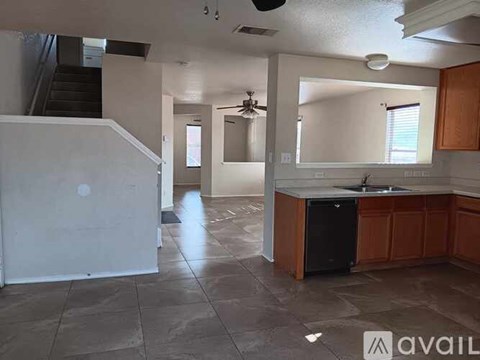 A kitchen with a black dishwasher and brown cabinets.