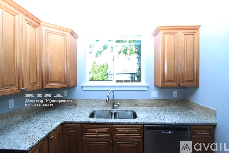A kitchen with wooden cabinets and a window showing greenery outside.
