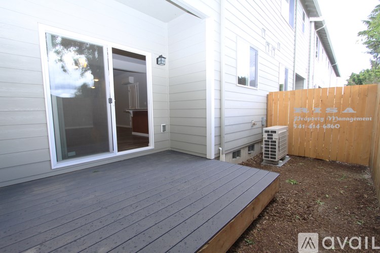 A wooden deck with a glass door and a sign on the fence.