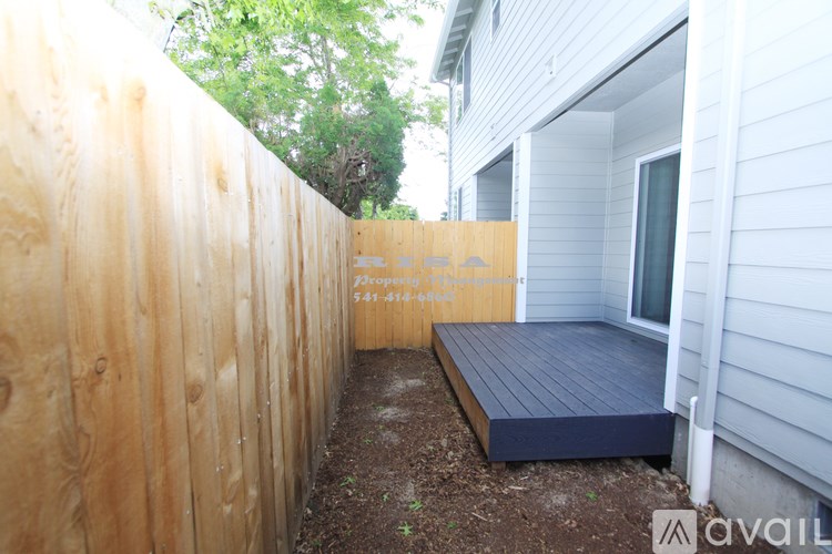 A wooden fence with a sign that says "For Sale" in front of a house.