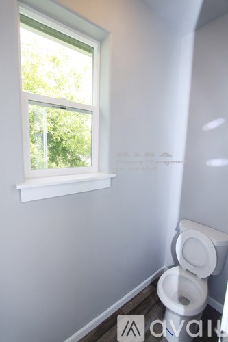 A white toilet sits in a bathroom next to a window.
