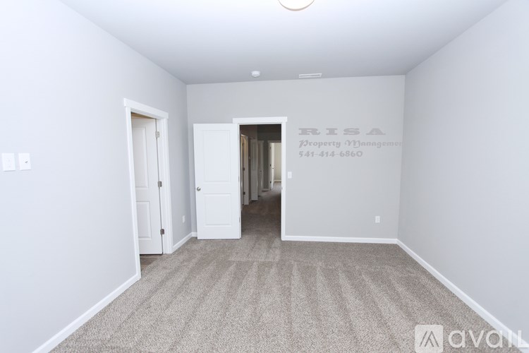A room with carpeted floor and a doorway leading to another room.