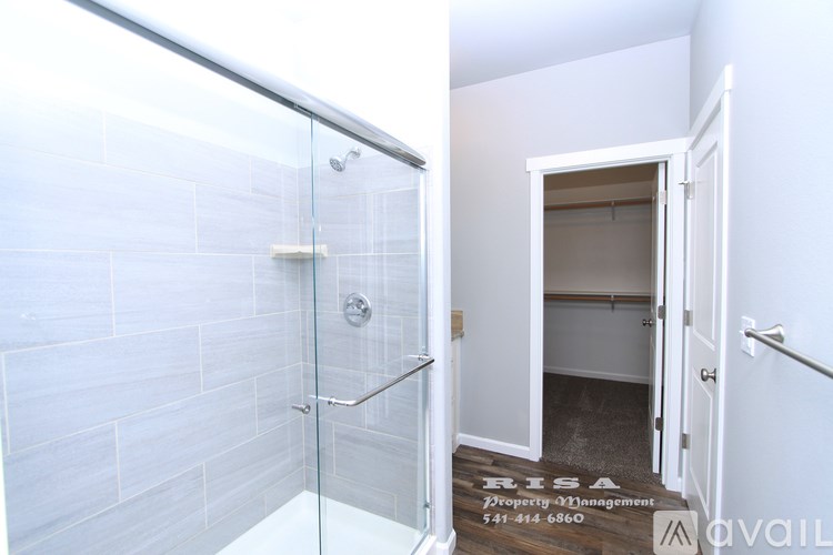 A bathroom with a glass shower door and a white tiled wall.