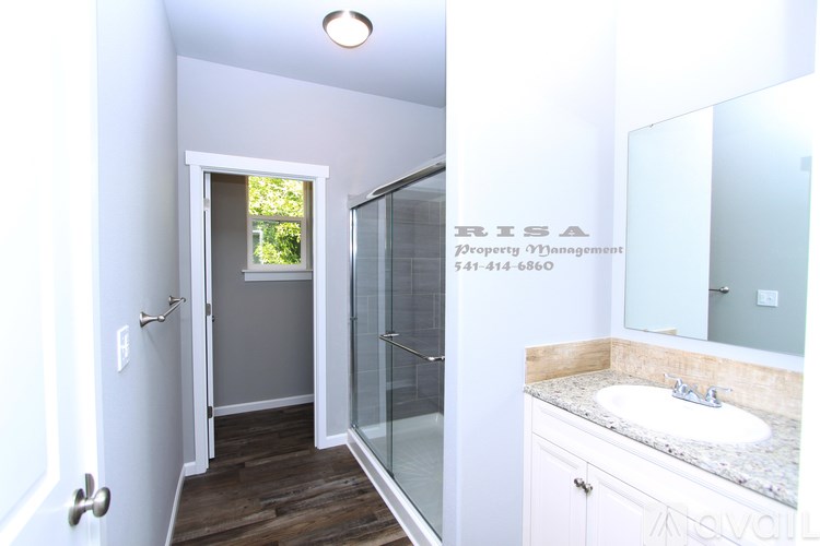 A bathroom with a sink, mirror, and shower.