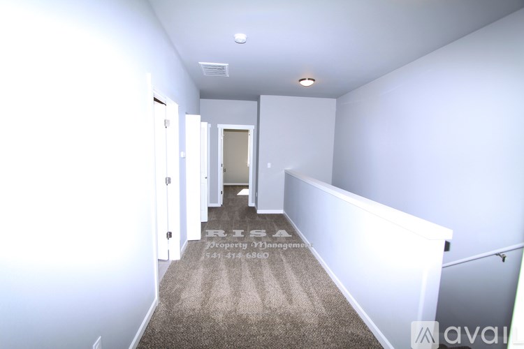 A hallway with a carpeted floor and white walls.