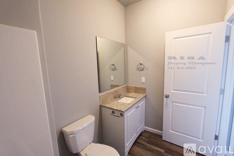 A bathroom with a sink, toilet and mirror.