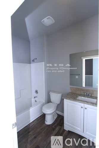 A bathroom with a toilet, sink and mirror.