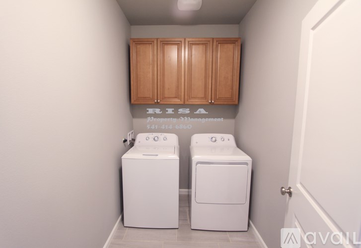 A laundry room with two washing machines and a cabinet above them.