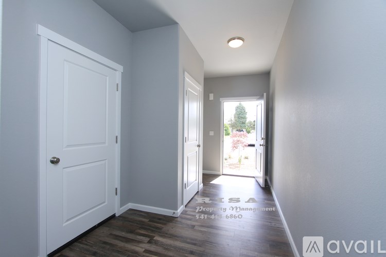 A hallway with a door on the left and a view of a backyard through an open door on the right.