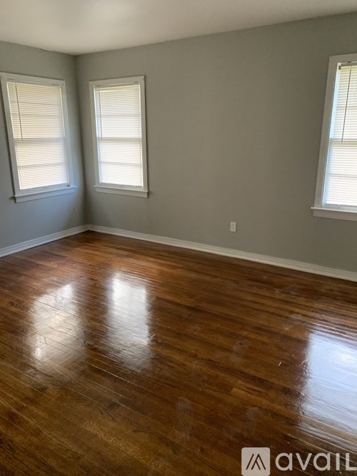 A room with wooden floors and two windows.