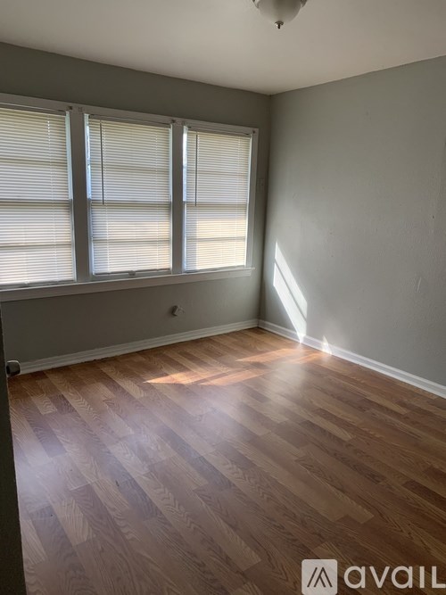A room with wooden flooring and a window with blinds.