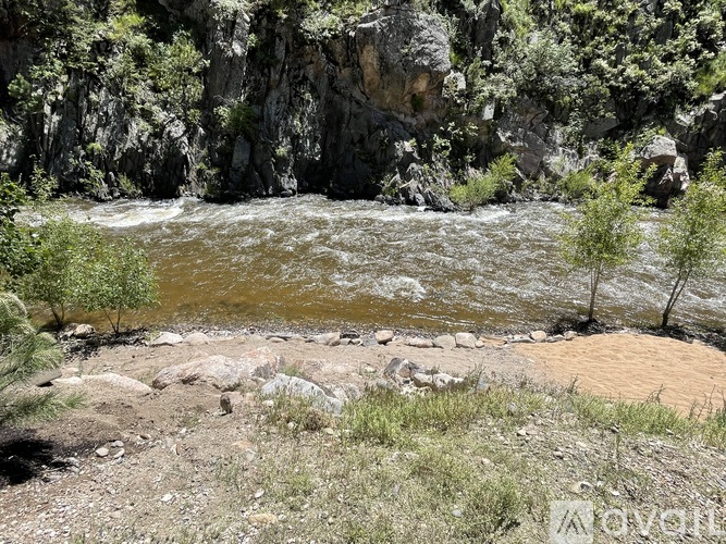 A river flows through a rocky landscape with trees and shrubs.