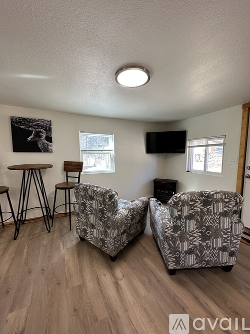 A living room with two chairs and a TV mounted on the wall.