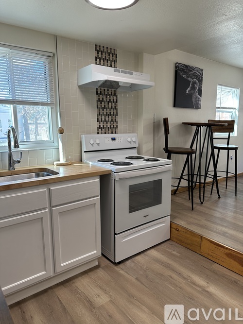 A kitchen with a white oven and a wooden floor.