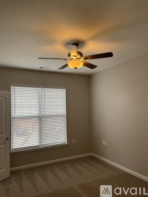 A room with a ceiling fan and a window with blinds.