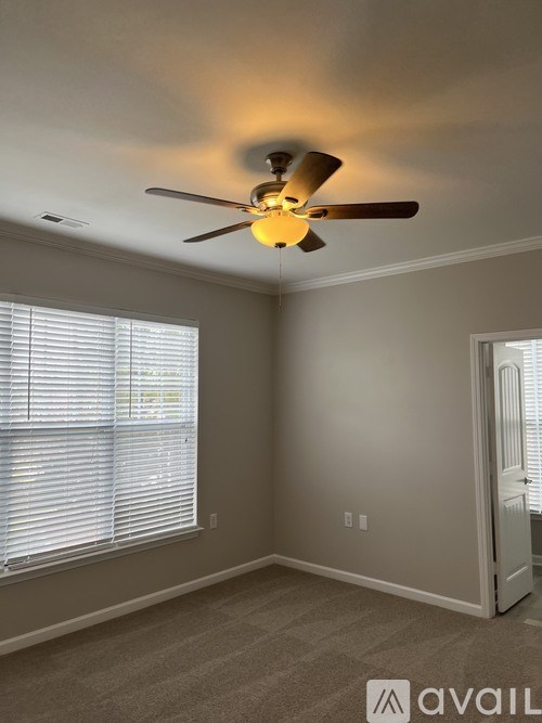 A room with a ceiling fan and a window with blinds.