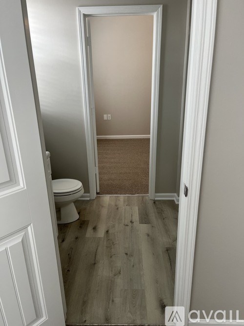 A bathroom with a toilet and wooden flooring.